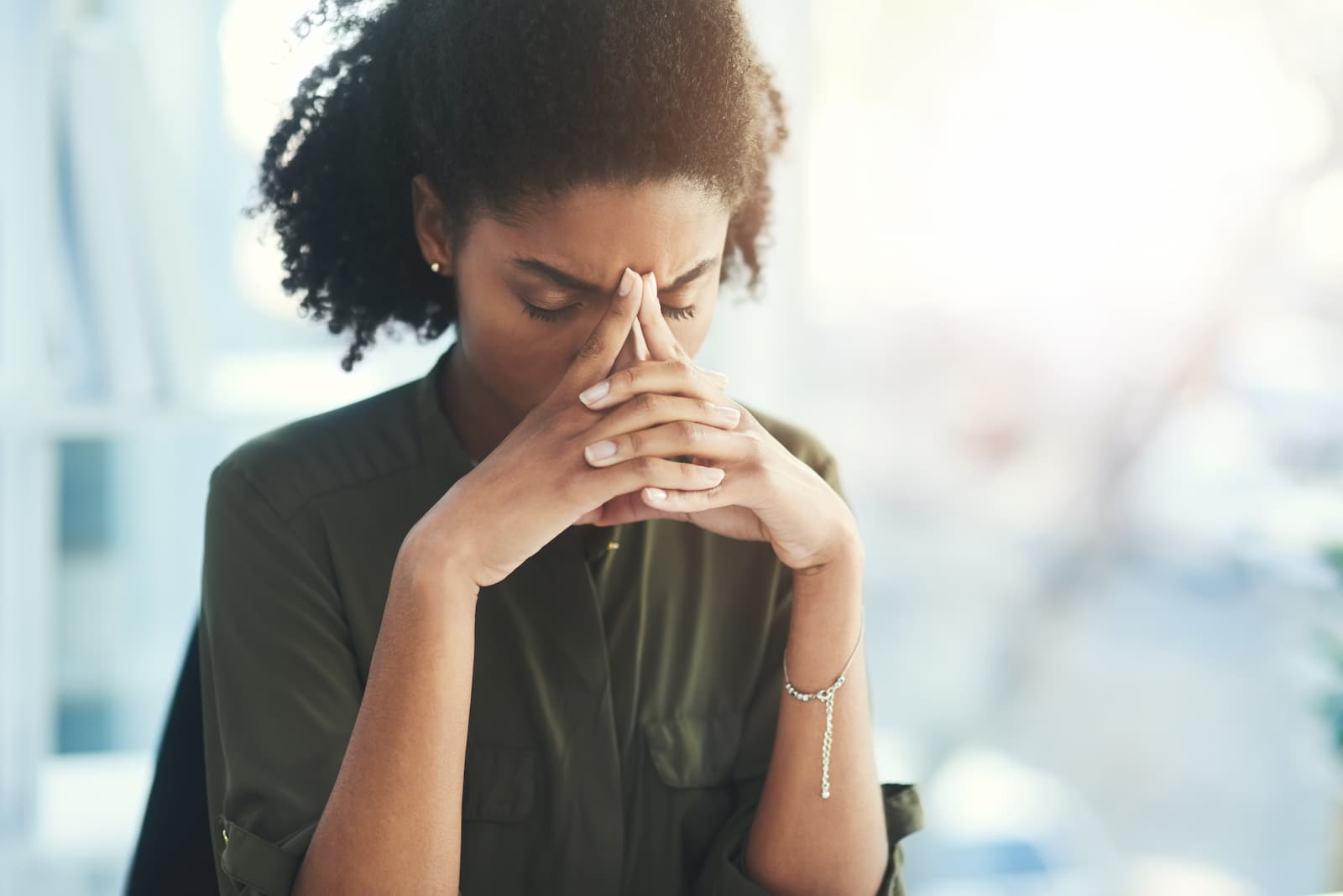 a women folding her hands in front of her forehead with closed eyes.